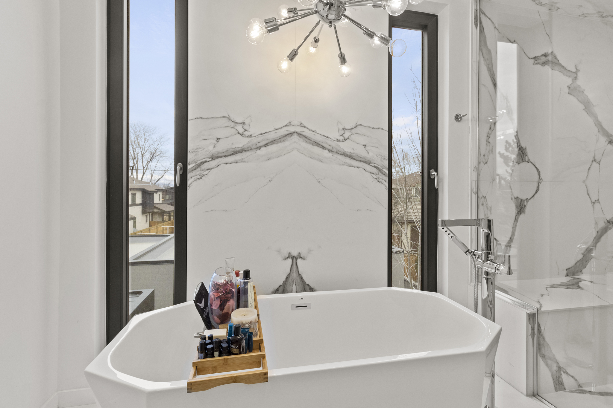 Custom-built Colorado bathroom with marble walls, freestanding tub, and modern chandelier Product Photography Littleton Colorado