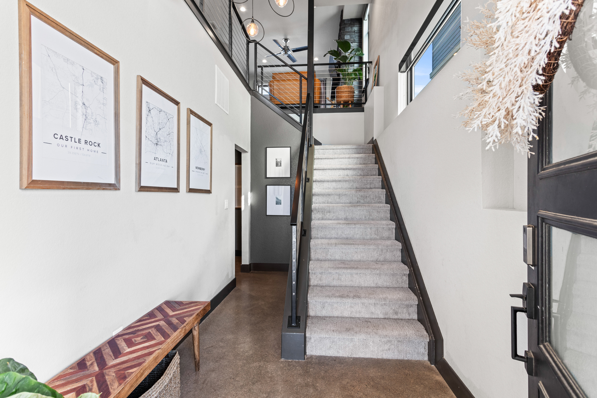 Custom-built Castle Rock entryway with carpeted stairs, pendant lights, and wooden bench Interior staging Photography