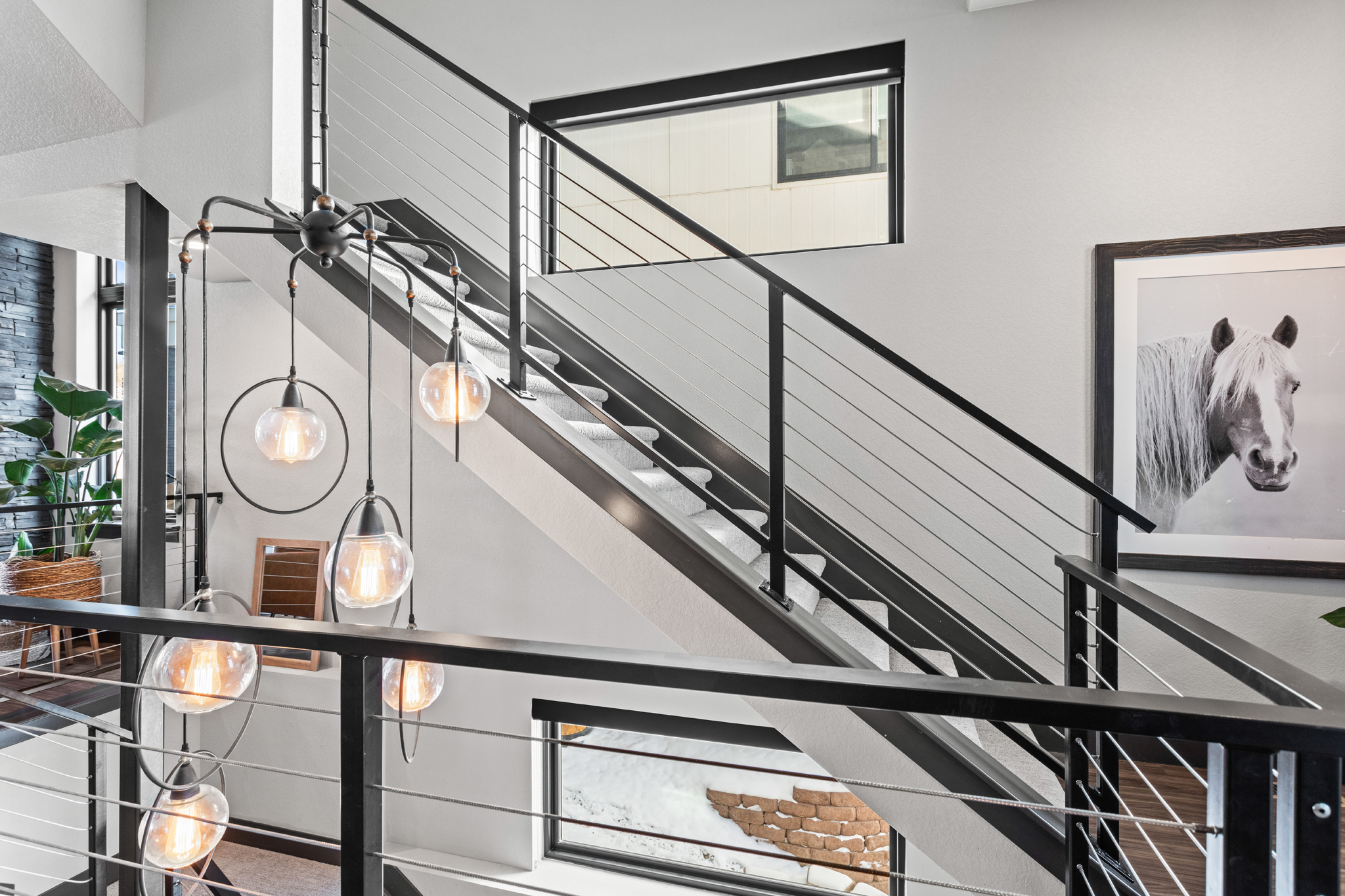 Modern Colorado home staircase with black metal railing, globe pendant lights, and contemporary staging decor interior design photography littleton colorado